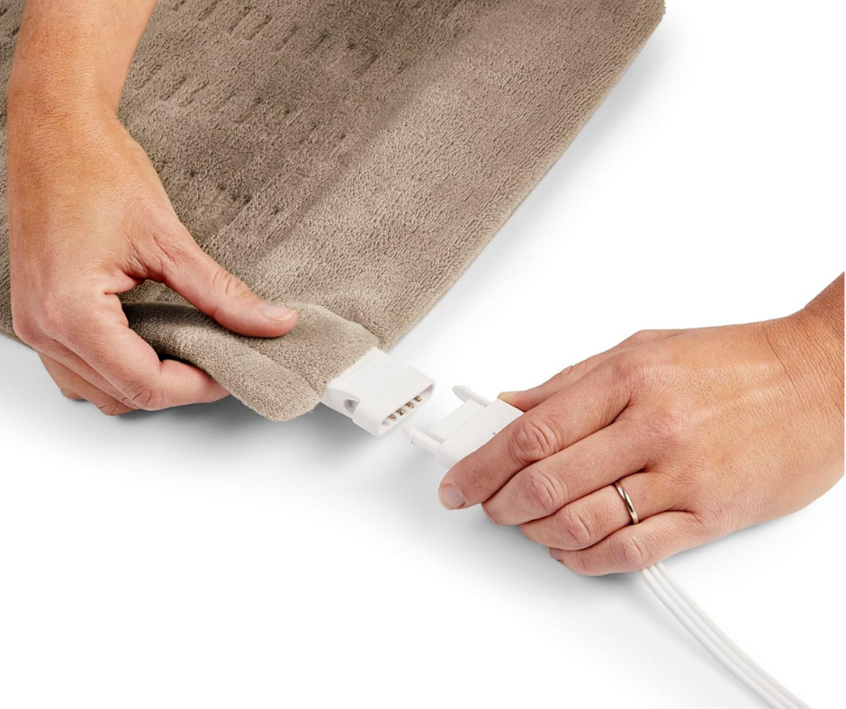 Hands plugging the power cord into a Sunbeam king size heating pad connector